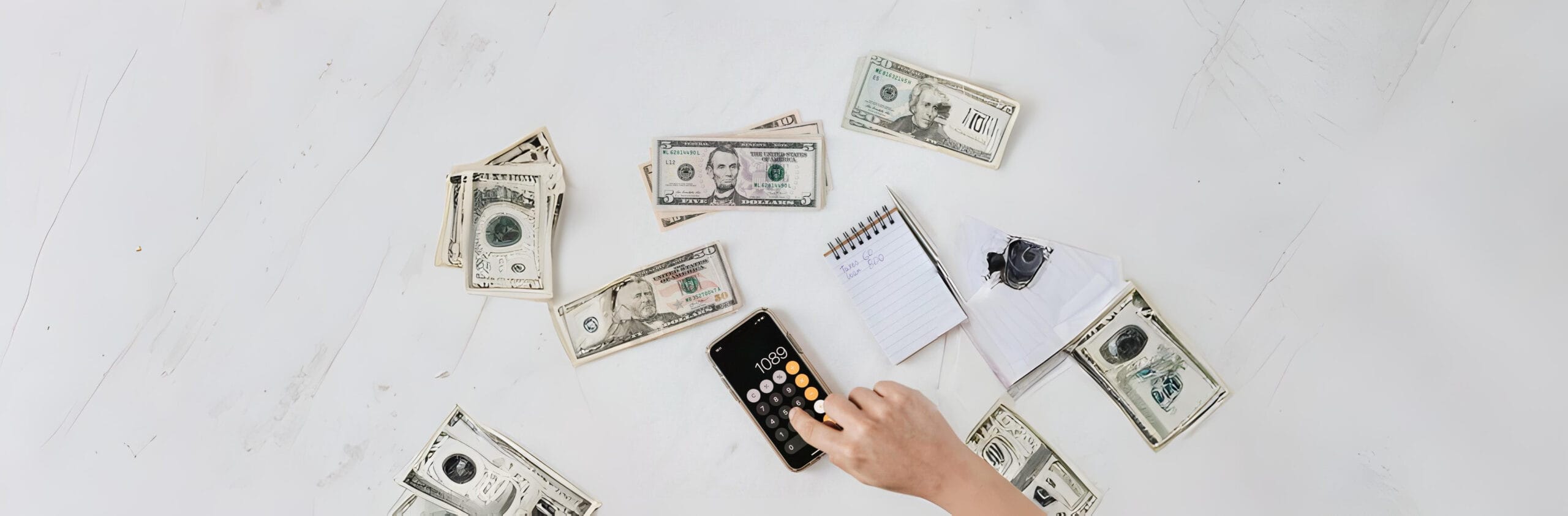 Entrepreneur calculating startup finances with cash, notes, and a calculator on a desk — planning the financial side of starting a business.